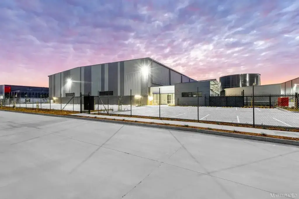 Front view of industrial warehouse in Carole Park with metal roofing completed by Envy Roofing at sunset