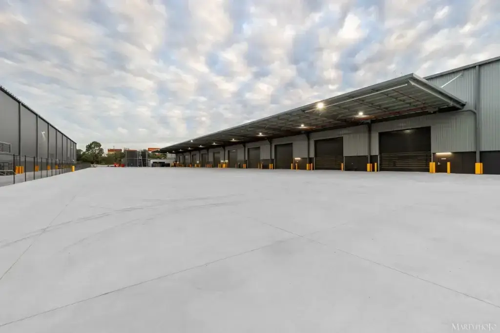 Side view of industrial warehouse in Carole Park with metal cladding and landscaped surrounds by Envy Roofing